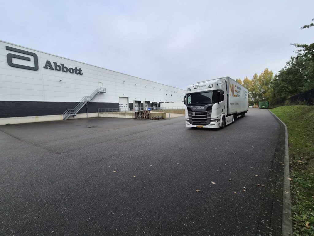 Witte VG-trekker met oplegger bij een bedrijfslocatie
