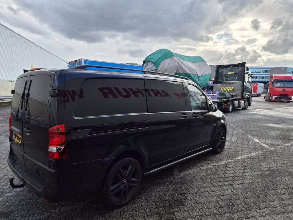 Bestelwagen naast exceptioneel transport met afgedekte lading